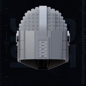 May include: A gray, geometric helmet constructed from small, square blocks. The helmet has a rounded top and a rectangular faceplate with a series of horizontal lines. The image includes the text "2020", "TEST PRINTED AMS COLORED STL", and "YOSH STUDIOS".