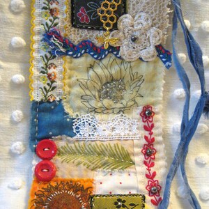 May include: Handmade fabric bookmark with a patchwork design. Features a sunflower, floral embroidery, red buttons, and a gold bee charm. Includes a blue ribbon for easy placement in books. A unique, handcrafted item.