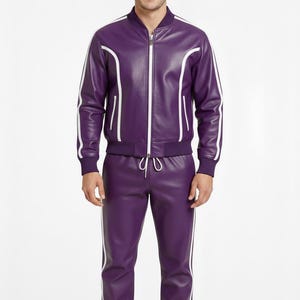 Peut inclure: Un surv&ecirc;tement en cuir violet assorti avec des rayures blanches. La veste est de style bombardier avec une fermeture &eacute;clair. Le pantalon a une taille &agrave; cordon et est resserr&eacute; aux chevilles. L'ensemble est port&eacute; par une personne.