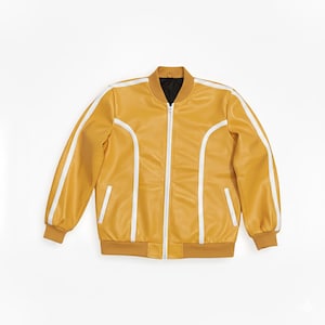 Peut inclure: Veste de bombardier jaune moutarde avec des rayures blanches sur les manches et sur les c&ocirc;t&eacute;s. La veste a une fermeture &eacute;clair sur le devant, deux poches avant et une doublure int&eacute;rieure noire. Le col et les poignets sont d'une nuance plus fonc&eacute;e de jaune moutarde.