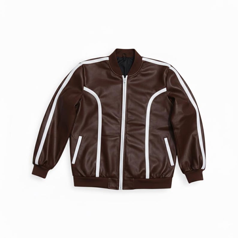 Peut inclure: Veste de bombardier marron avec des rayures blanches sur les manches et des accents blancs. La veste a une fermeture &eacute;clair, deux poches avant et un col et des poignets c&ocirc;tel&eacute;s. Fabriqu&eacute; dans un mat&eacute;riau lisse semblable au cuir.