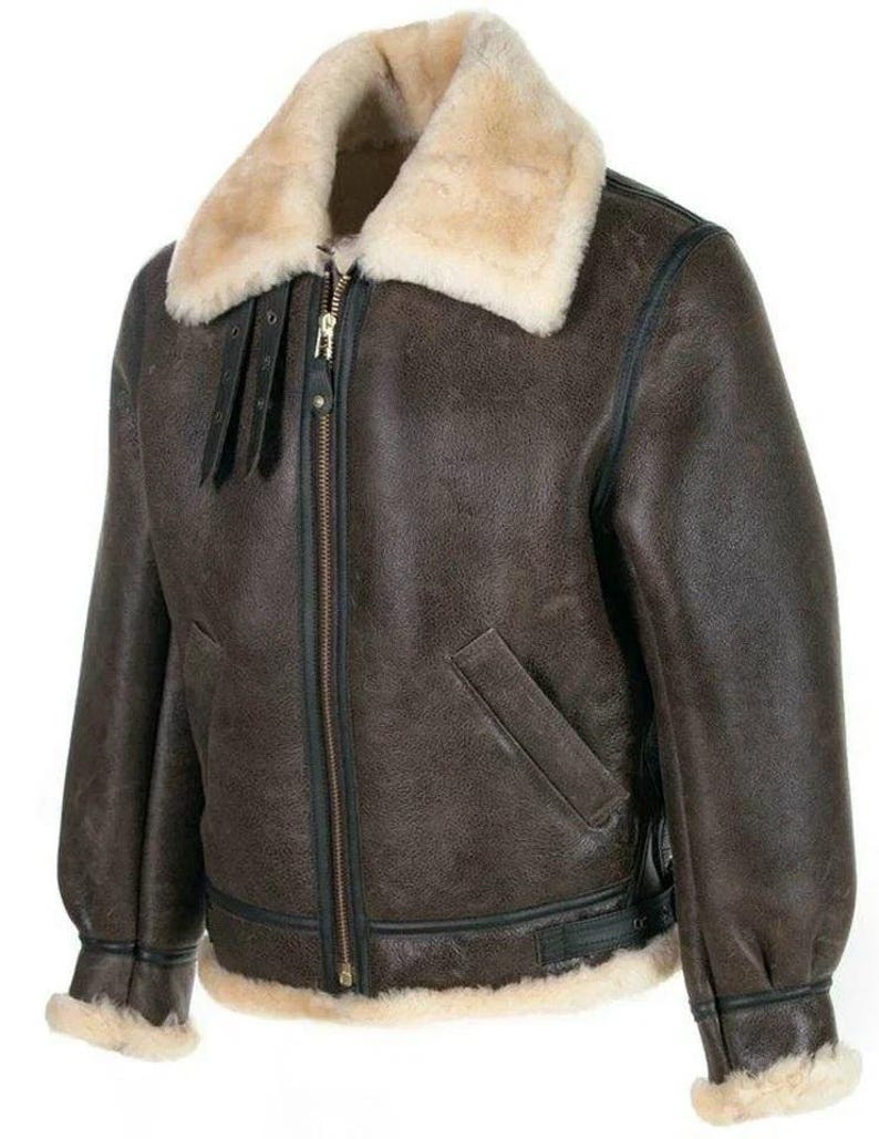 K&ouml;nnte beinhalten: Eine dunkelbraune Lederjacke mit einem dicken, cremefarbenen Lammfellkragen und &Auml;rmelb&uuml;ndchen. Die Jacke verf&uuml;gt &uuml;ber einen zentralen Metallrei&szlig;verschluss, zwei schr&auml;ge Vordertaschen, schwarze Lederbes&auml;tze und zwei kleine verstellbare Riemen am Kragen.