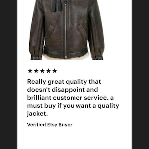 K&ouml;nnte beinhalten: Eine dunkelbraune Lederjacke mit einem cremefarbenen Lammfellkragen und Innenfutter. Die Jacke verf&uuml;gt &uuml;ber einen zentralen Metallrei&szlig;verschluss, schwarze Lederbes&auml;tze und zwei verstellbare Schnallenriemen im oberen Brustbereich.