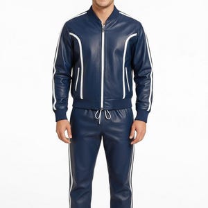 Peut inclure: Un surv&ecirc;tement en cuir bleu marine compos&eacute; d'une veste bomber zipp&eacute;e et d'un pantalon assorti. La veste et le pantalon ont des rayures blanches sur les c&ocirc;t&eacute;s. Un ensemble sportif et &eacute;l&eacute;gant.