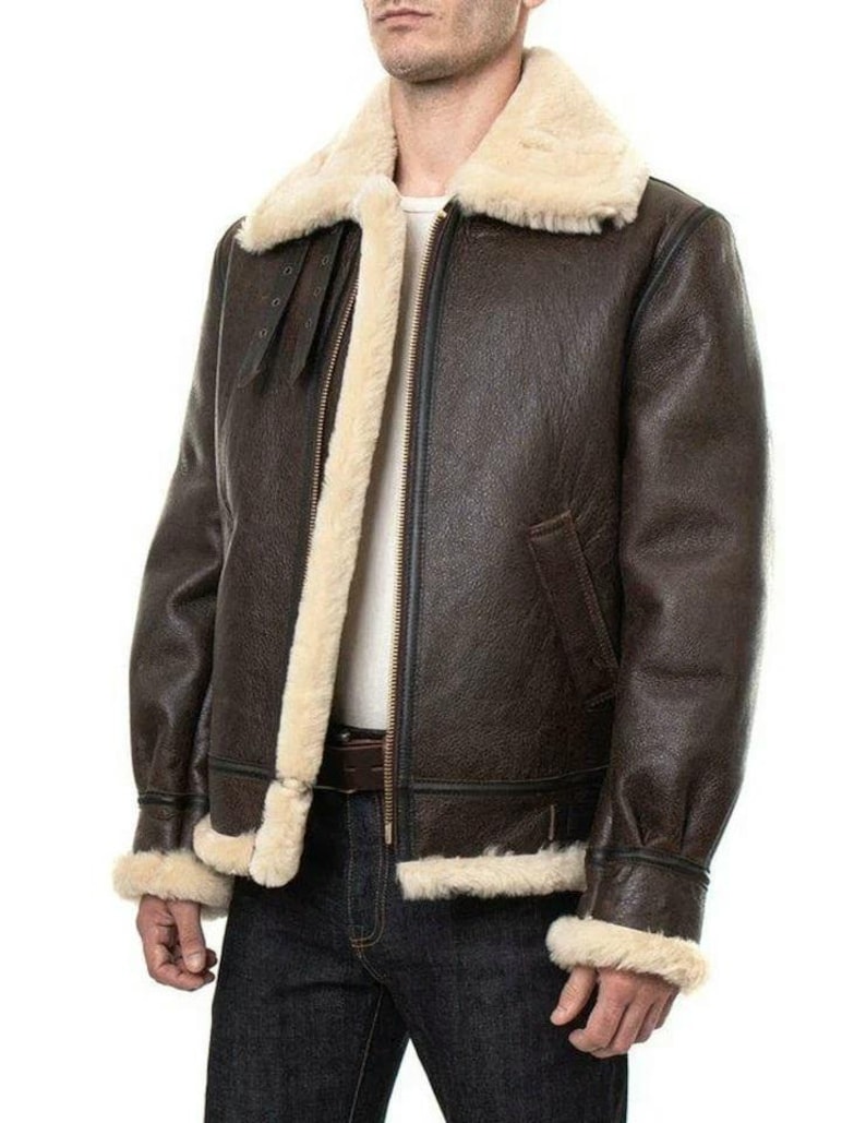 K&ouml;nnte beinhalten: Eine dunkelbraune Leder-Bomberjacke mit dickem, cremefarbenem Lammfellfutter, einem breiten Umlegekragen, einem durchgehenden Frontrei&szlig;verschluss und verstellbaren Schnallenriemen am Hals. Die &Auml;rmelb&uuml;ndchen und der Saum sind mit passendem Lammfell besetzt.
