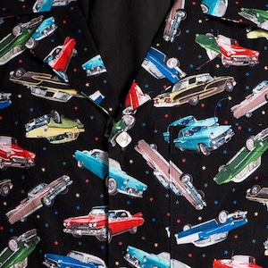 May include: A black and white patterned shirt with a repeating design of vintage cars. The cars are in various colors, including red, blue, green, and yellow. The shirt has a button-up collar and short sleeves.