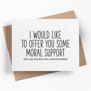 May include: A white greeting card with black text that reads "I WOULD LIKE TO OFFER YOU SOME MORAL SUPPORT (but my morals are questionable)". The card is inside a brown envelope.