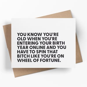 May include: A white greeting card with black text that reads: YOU KNOW YOU'RE OLD WHEN YOU'RE ENTERING YOUR BIRTH YEAR ONLINE AND YOU HAVE TO SPIN THAT BITCH LIKE YOU'RE ON WHEEL OF FORTUNE. The card is placed on top of a brown paper envelope.