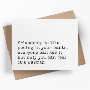 May include: A white rectangular greeting card featuring black typewriter-style text that reads: friendship is like peeing in your pants. everyone can see it but only you can feel it's warmth. The card is placed on top of a brown kraft paper envelope.