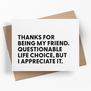 May include: A white greeting card with black text that reads: "THANKS FOR BEING MY FRIEND. QUESTIONABLE LIFE CHOICE, BUT I APPRECIATE IT." The card is on a brown envelope.