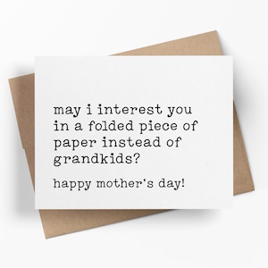 May include: A white greeting card with the text "may i interest you in a folded piece of paper instead of grandkids? happy mother's day!" is displayed on a brown envelope.