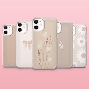 May include: A collection of five phone cases with floral and bow designs. The cases feature a clear, protective design with various beige and white patterns, including hearts, daisies, and botanical illustrations. The cases are displayed against a pink background.