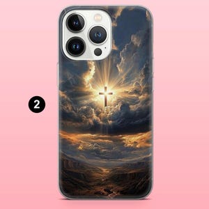 May include: A phone case featuring a dramatic landscape with a cross illuminated by a bright light. The design includes a cross in the center, surrounded by clouds and a canyon scene below. The case has a clear border and a number 2 in a black circle.