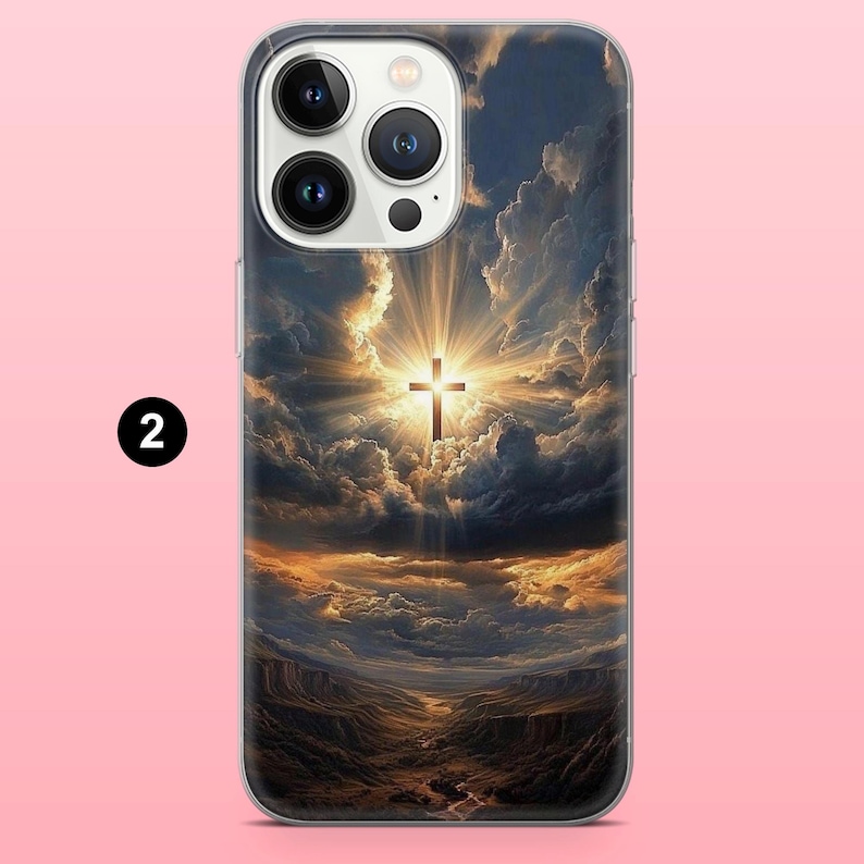 May include: A phone case featuring a dramatic landscape with a cross illuminated by a bright light. The design includes a cross in the center, surrounded by clouds and a canyon scene below. The case has a clear border and a number 2 in a black circle.