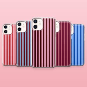 Peut inclure: Une collection de cinq coques de téléphone avec des motifs à rayures verticales de différentes couleurs. Les coques présentent des rayures rouges, bleues et des nuances de rose et de bordeaux. Les coques sont disposées en rangée sur un fond rose.