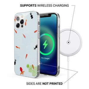 May include: Clear phone case with a koi fish design. The case is shown with a phone displaying a charging screen and a wireless charger. The text reads: "SUPPORTS WIRELESS CHARGING" and "SIDES ARE NOT PRINTED".