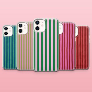 Puede incluir: Cinco fundas para teléfono con diseños de rayas verticales en varios colores, incluyendo verde, rosa y rojo. Las fundas tienen un borde transparente y están dispuestas sobre un fondo rosa.