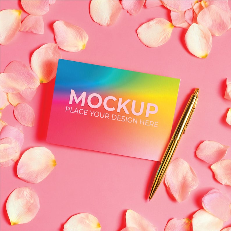 May include: A colorful mockup card with the word "MOCKUP" and the text "PLACE YOUR DESIGN HERE" is surrounded by pink rose petals on a pink background. A gold pen rests on the right side of the card.