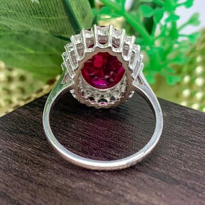 Vintage-inspired lab-created ruby engagement ring with an oval red gemstone and halo design.