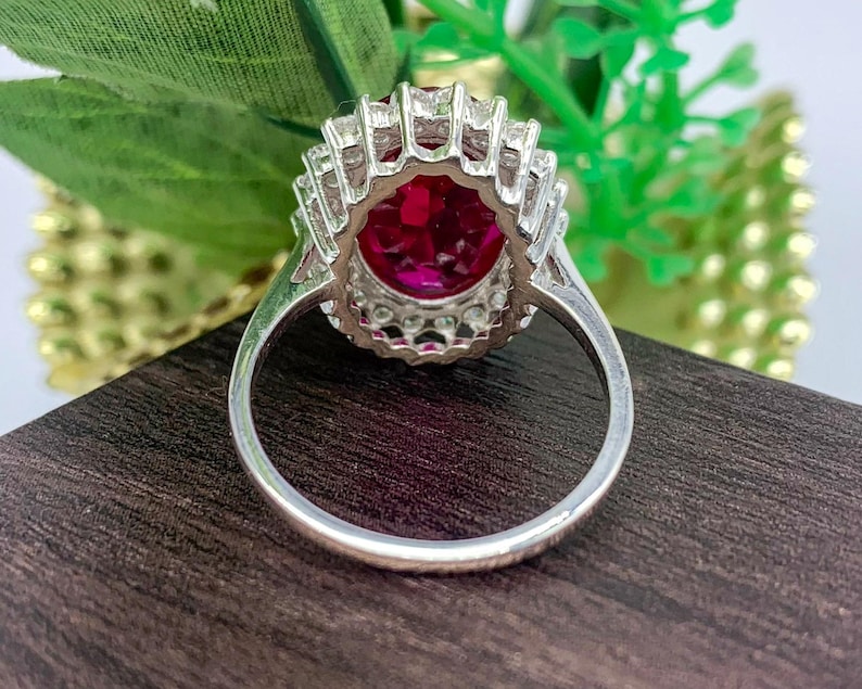 Vintage-inspired lab-created ruby engagement ring with an oval red gemstone and halo design.