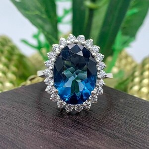 Vintage-inspired lab-created sapphire engagement ring with an oval blue gemstone and halo design.