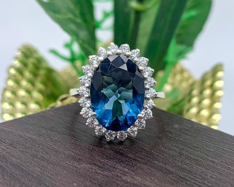 Vintage-inspired lab-created sapphire engagement ring with an oval blue gemstone and halo design.