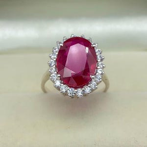 Close-up of an oval lab-created ruby ring with a sparkling halo setting in polished sterling silver.
