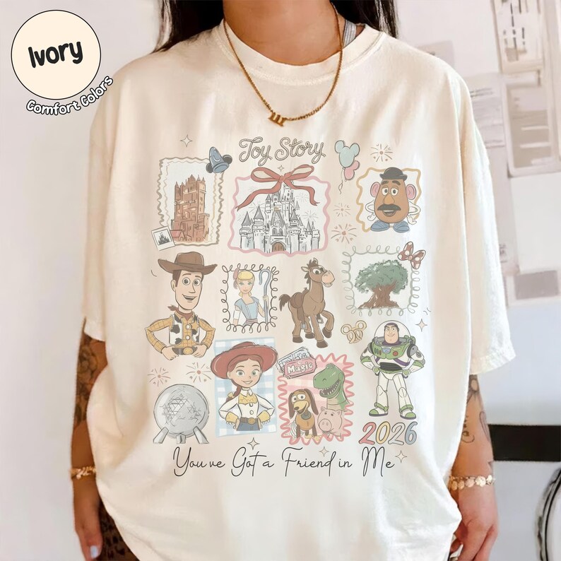 May include: Ivory-colored t-shirt featuring a colorful Toy Story graphic. The design includes various characters and elements from the movie, such as Woody, Buzz Lightyear, and a castle. The text "Toy Story" and "You've Got a Friend in Me" are also visible.