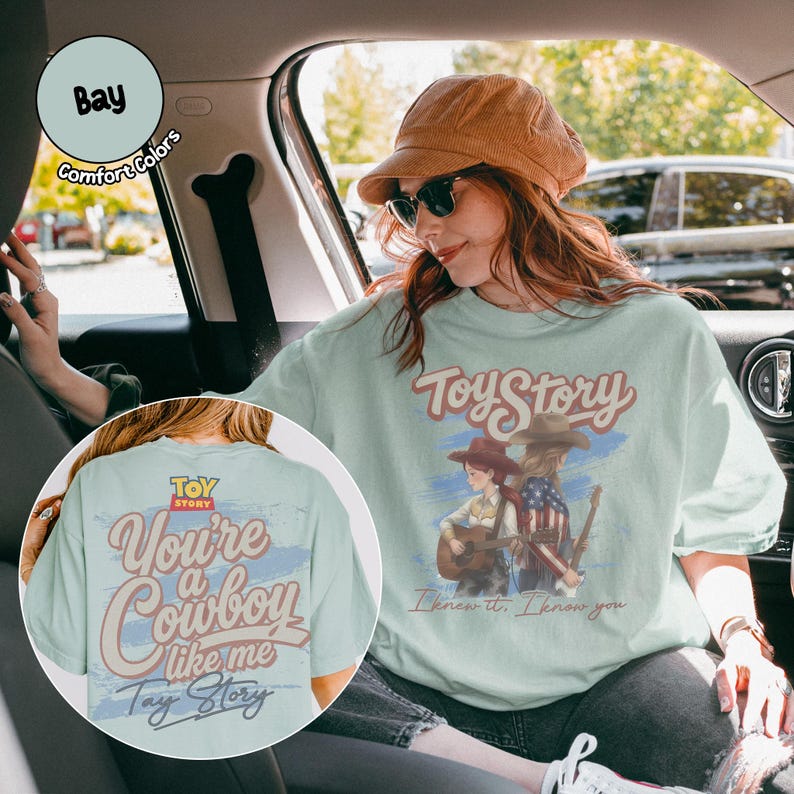 May include: A light green t-shirt featuring a graphic of two figures with guitars and the text Toy Story I knew it. I know you. The back of the shirt displays the text You're a Cowboy like me Toy Story over a blue brushstroke background.