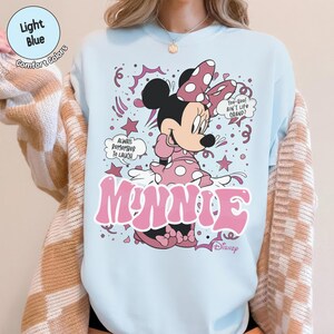 May include: Light blue Minnie Mouse graphic t-shirt. The design features Minnie Mouse in a pink polka dot dress and bow, with the word "Minnie" in pink. Text includes "Always Remember to Laugh" and "Too-Woo! Ain't Life Grand?"