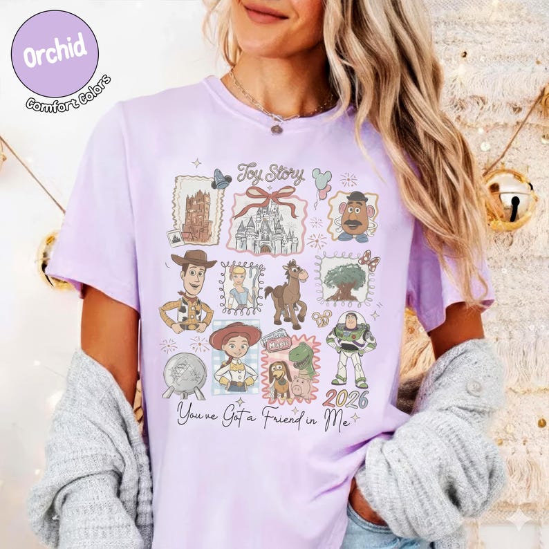 May include: A light purple t-shirt featuring a collage of Toy Story characters and imagery. The design includes illustrations of Woody, Buzz Lightyear, and other characters, along with the text "Toy Story" and "You've Got a Friend in Me."