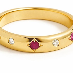 Peut inclure: Une bague en or avec une finition polie. La bague est ornée de trois pierres précieuses rouges en forme de diamant et de deux pierres précieuses claires. Les pierres précieuses sont serties dans le jonc en or, créant un design classique et élégant.