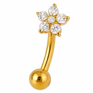 Könnte beinhalten: Ein goldfarbener, gebogener Piercing-Schmuck mit einem Blumendesign. Die Blume besteht aus sechs klaren, rund geschliffenen Edelsteinen. Der Stab hat unten eine kleine, runde Kugel.