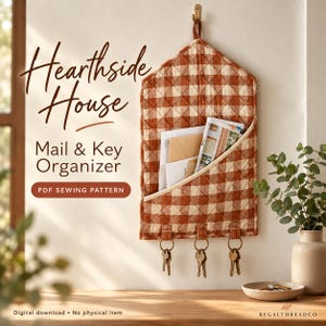 Può includere: Un organizer da parete trapuntato per posta e chiavi con un motivo a quadretti vichy color ruggine e crema. L'organizer presenta una tasca diagonale contenente buste e tre anelli metallici per le chiavi. Il testo recita Hearthside House Mail & Key Organizer PDF SEWING PATTERN.