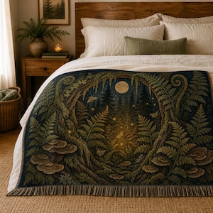 Op de afbeelding: Een geweven sprei met een bosscène met een volle maan, varens en paddenstoelen. De deken heeft een donkerblauwe achtergrond met bruine en groene details. De deken ligt op een bed met wit beddengoed en een houten hoofdbord.