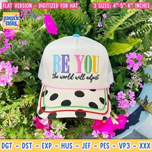 May include: A white trucker hat featuring the embroidered text BE YOU the world will adjust in multicolored letters. The brim has a black polka dot pattern with red and green trim. The hat is available in 4, 5, and 6 inch sizes.