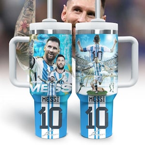 May include: Two stainless steel tumblers featuring images of Lionel Messi in an Argentina soccer uniform. The tumblers have white handles, lids, and straws. The design includes the word "MESSI" and the number "10" in a blue and white color scheme.