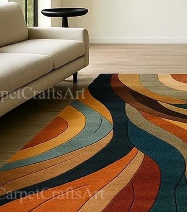 May include: A vibrant area rug with an abstract, flowing pattern. The rug showcases curved lines in shades of orange, brown, blue, and beige. It's positioned on a wooden floor, with a beige sofa and black side table visible in the background.