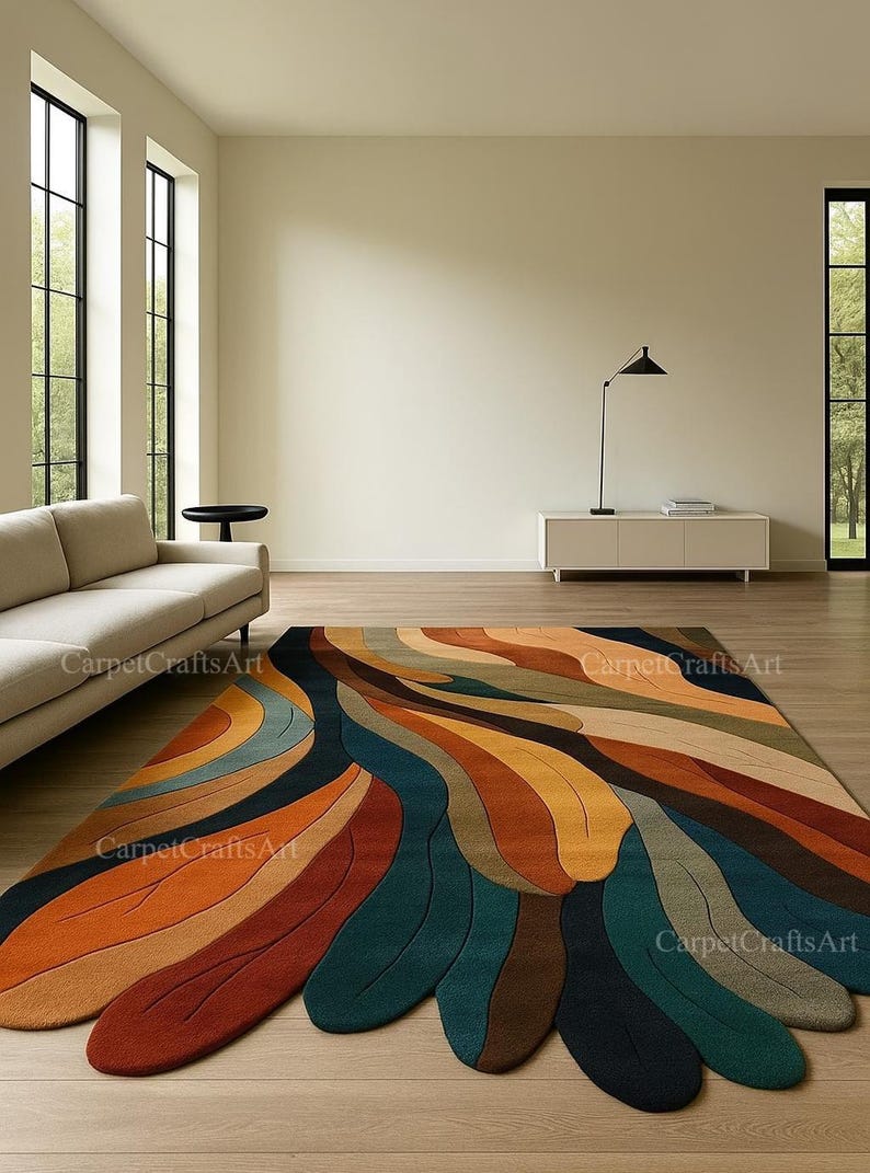 May include: A large, colourful area rug with an abstract design. The rug features flowing, feather-like shapes in shades of orange, brown, teal, and blue. The rug is placed on a wooden floor in a modern living room setting.