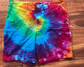 May include: Tie-dye shorts in a vibrant rainbow of colors, including blue, green, yellow, orange, and purple. The shorts have a button closure, belt loops, and pockets. The shorts are made of a soft, comfortable material.
