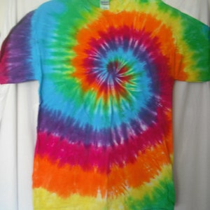Puede incluir: Una camiseta tie-dye con un patr&oacute;n de espiral arco&iacute;ris en tonos de verde, azul, morado, rosa, naranja y amarillo.