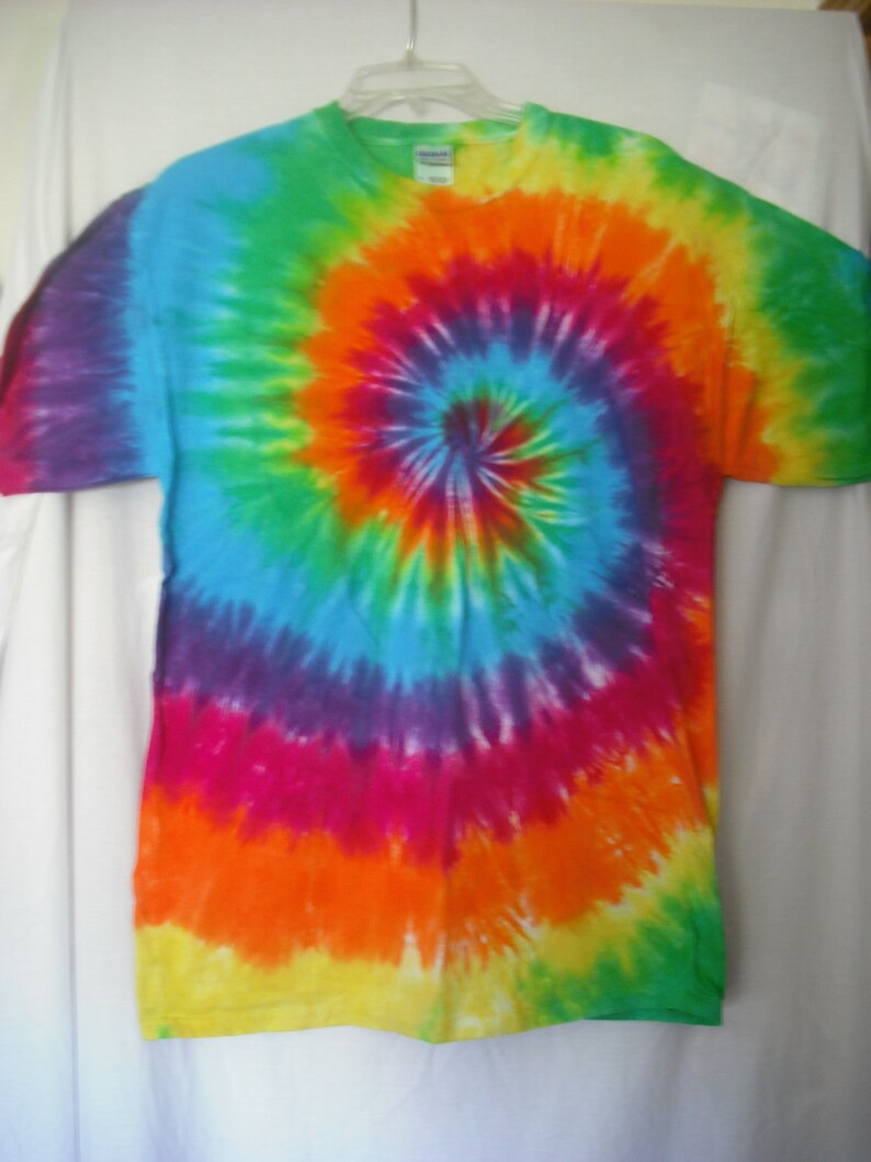 Puede incluir: Una camiseta tie-dye con un patr&oacute;n de espiral arco&iacute;ris en tonos de verde, azul, morado, rosa, naranja y amarillo.