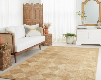 Puede incluir: Una alfombra rectangular grande de yute con un patrón geométrico de diamantes en tonos beige y marrón claro. La alfombra está colocada en un salón, complementando los tonos neutros de los muebles y la decoración. La alfombra añade textura y calidez al espacio.