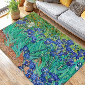 Può includere: Un tappeto rettangolare con un design floreale con iris blu, foglie verdi e un bordo marrone. Il design del tappeto ricorda un dipinto, con pennellate visibili e una vivace tavolozza di colori. Il tappeto è posato su un pavimento in legno.