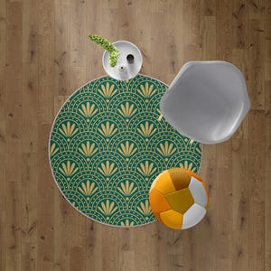 May include: Overhead view of a round green and gold patterned rug with a white border. A gray chair, a white vase with greenery, and a multi-colored soccer ball are also visible on a wooden floor.