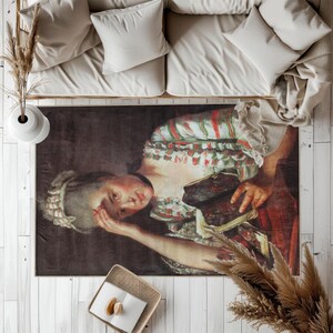 May include: A rectangular area rug featuring a classical painting of a woman in a red and green dress, holding a book. The rug has a dark background and is placed under a beige sofa.