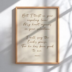 Può includere: Una stampa incorniciata con sfondo beige chiaro e cornice in legno. La stampa presenta un testo elegante, in stile scritto a mano, di colore marrone caldo, tra cui le parole "But I trust in your unfailing love." Il testo è una citazione dal Salmo 13.