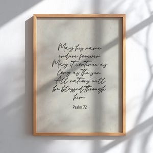 Op de afbeelding: Een ingelijste print met een lichtbeige achtergrond en zwart schrift. De tekst luidt: "Moge zijn naam voor altijd voortduren; Moge het voortduren zolang de zon. Alle naties zullen door hem gezegend worden. Psalm 72."