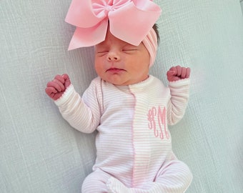 Può includere: Un body a righe rosa e bianche per neonato con un cerchietto a fiocco rosa e la lettera "M" ricamata sul davanti.