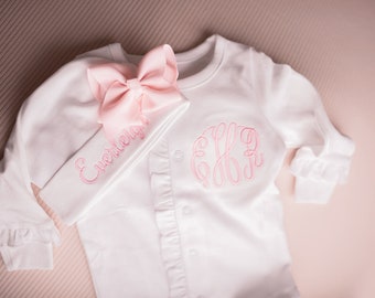 Puede incluir: Mono blanco para bebé con monograma bordado en rosa y mangas con volantes. Se incluye una diadema a juego con un gran lazo rosa y el nombre "Everleigh" bordado en rosa. El mono tiene una parte delantera abotonada.